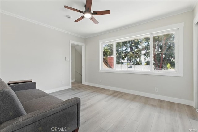 living area with ceiling fan, baseboards, ornamental molding, and wood finished floors