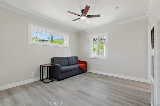 living area featuring crown molding, a heating unit, light wood-style floors, baseboards, and a ceiling fan