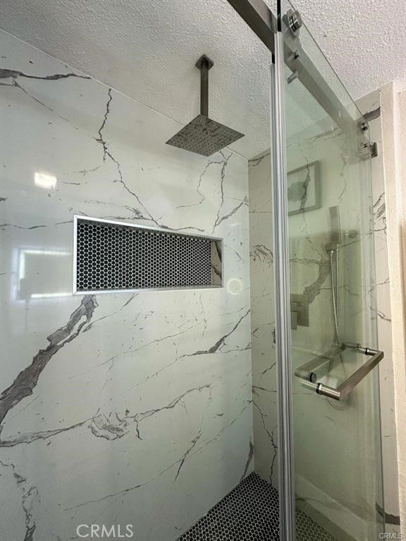 full bathroom featuring a marble finish shower and a textured ceiling