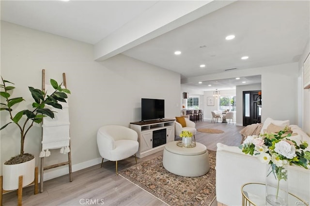 living room featuring light wood-style floors, recessed lighting, baseboards, and beamed ceiling