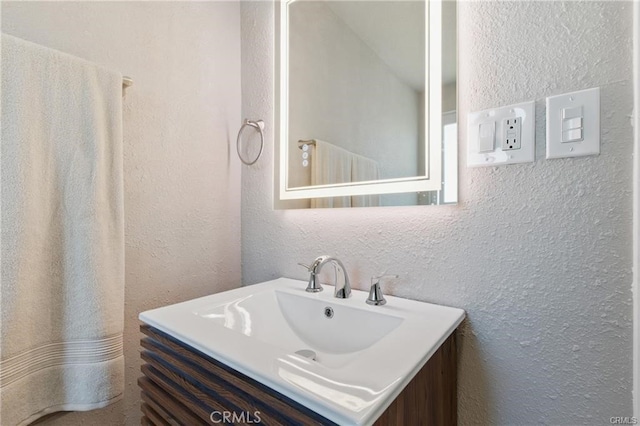 bathroom with a textured wall and vanity