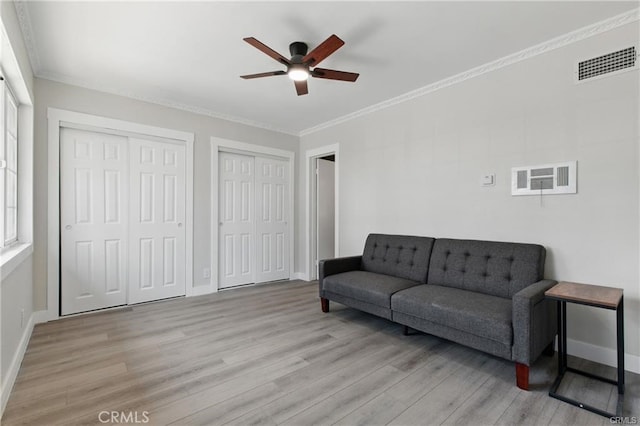 living area featuring light wood-style floors, baseboards, ceiling fan, and visible vents