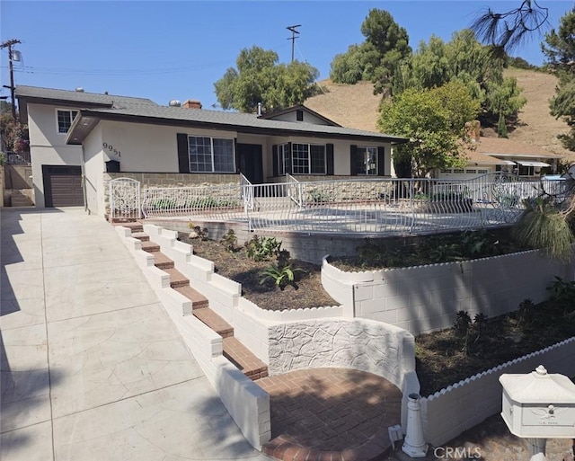 back of property featuring stucco siding, a garage, fence, and driveway