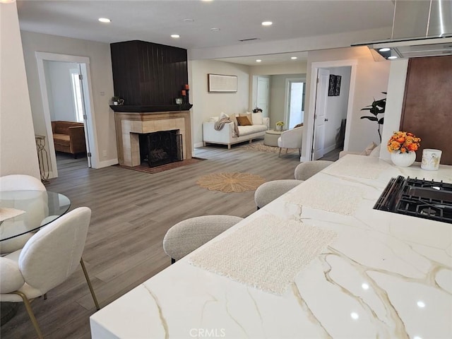 bedroom with recessed lighting, wood finished floors, and a tile fireplace