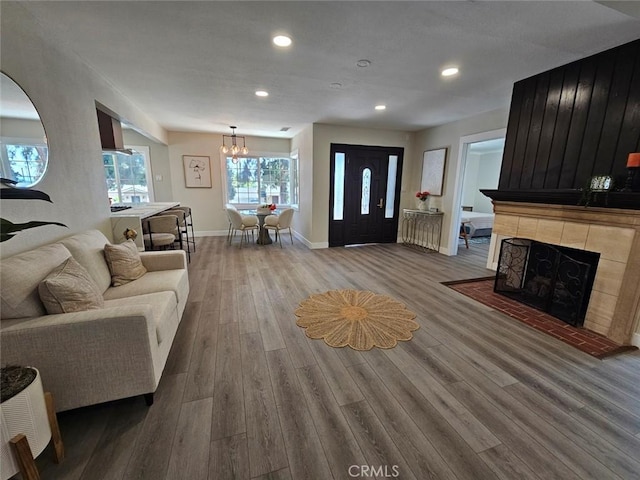 living area featuring wood finished floors, a fireplace, baseboards, recessed lighting, and a chandelier