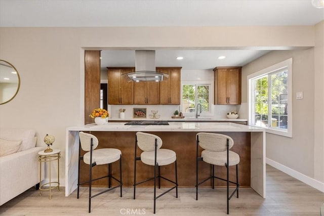 9951 Glencrest Cir, Sun Valley, CA 91504 - kitchen with a sink, brown cabinetry, island range hood, light wood-style flooring, and recessed lighting