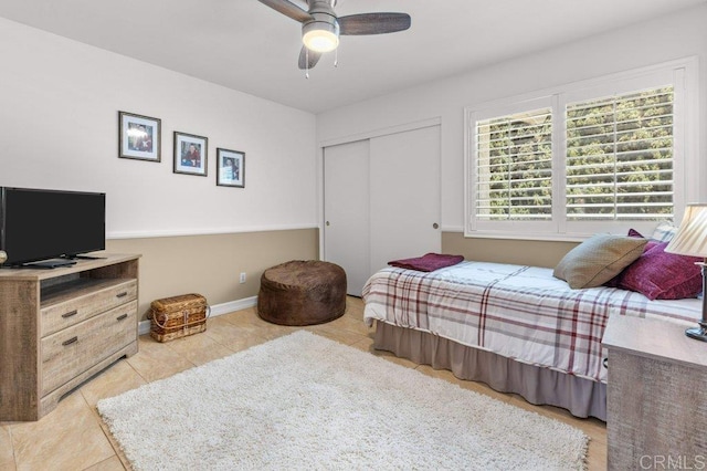 tiled bedroom with ceiling fan, baseboards, and a closet