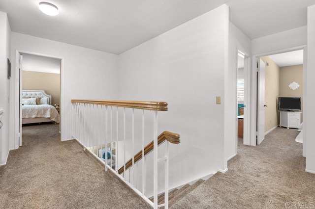 hall with baseboards, an upstairs landing, and carpet