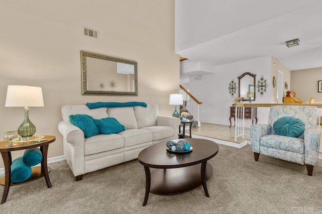living room featuring stairway, visible vents, baseboards, and carpet