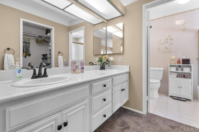 bathroom with a sink, tile patterned floors, toilet, and double vanity