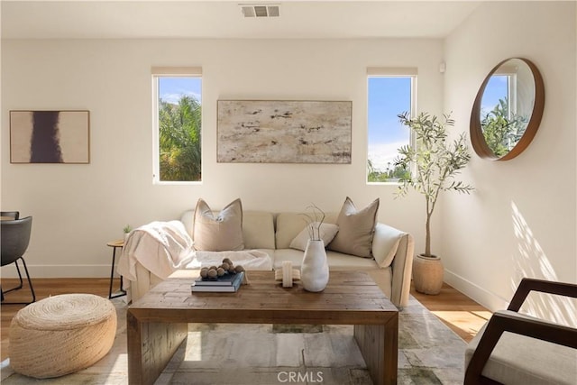 living area featuring visible vents, baseboards, and wood finished floors