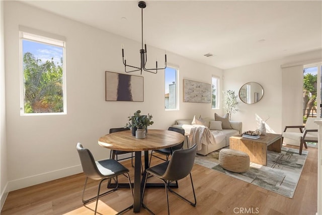 dining area with light wood-style floors, baseboards, visible vents, and a chandelier