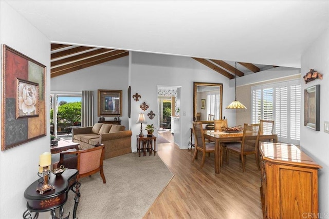 living room featuring vaulted ceiling with beams, light wood-style floors, and plenty of natural light