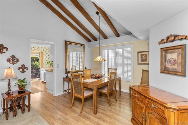 dining area featuring baseboards, lofted ceiling with beams, and light wood-style floors