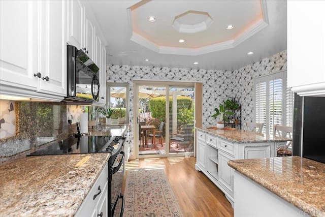kitchen featuring ornamental molding, white cabinetry, a tray ceiling, a sink, and black appliances