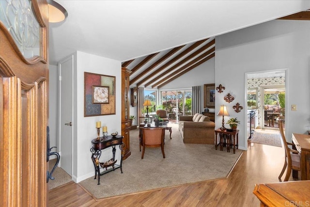 living area featuring baseboards, plenty of natural light, vaulted ceiling, and wood finished floors