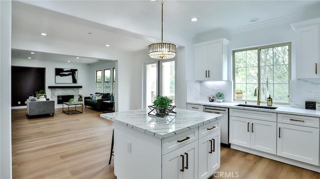 kitchen featuring a kitchen island, dishwasher, a sink, light wood finished floors, and white cabinetry