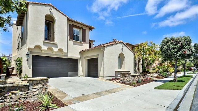 mediterranean / spanish-style home with a tiled roof, an attached garage, driveway, and stucco siding