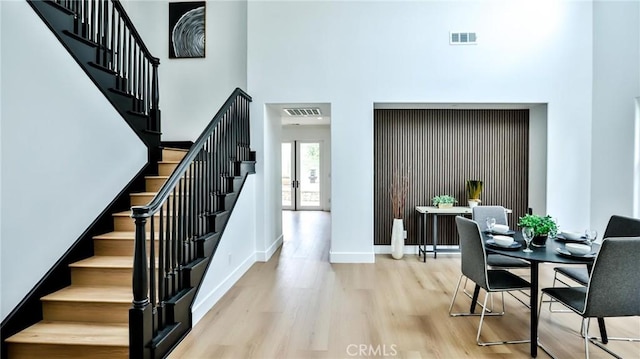 staircase featuring baseboards, visible vents, wood finished floors, and a towering ceiling