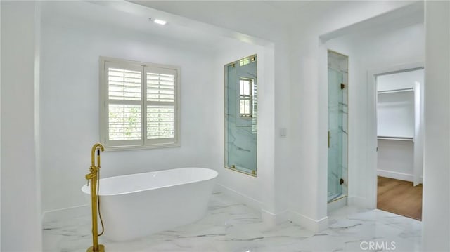 full bathroom featuring baseboards, marble finish floor, a spacious closet, a marble finish shower, and a soaking tub