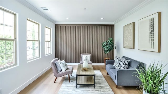 sitting room with visible vents, ornamental molding, and wood finished floors