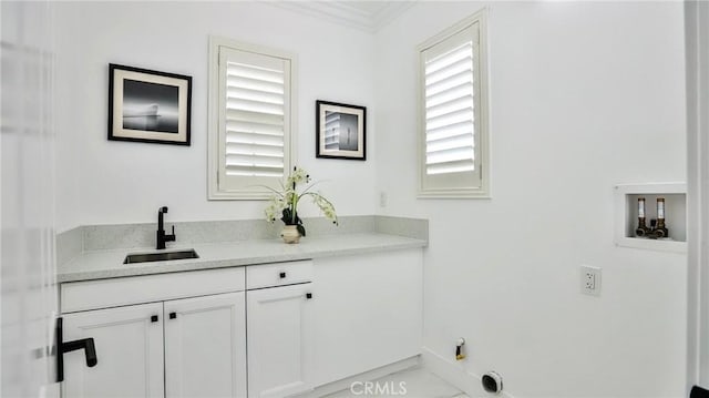 laundry area with ornamental molding, baseboards, cabinet space, a sink, and washer hookup