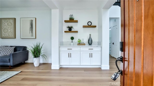 bar with crown molding and light wood-style floors