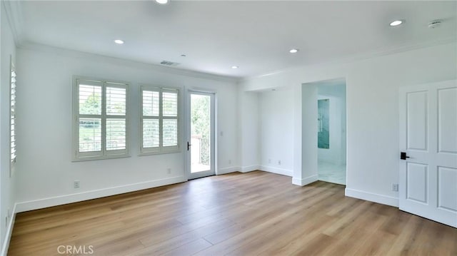 unfurnished room featuring crown molding, baseboards, light wood-type flooring, and visible vents