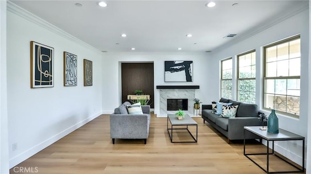 living room with recessed lighting, a high end fireplace, baseboards, and crown molding