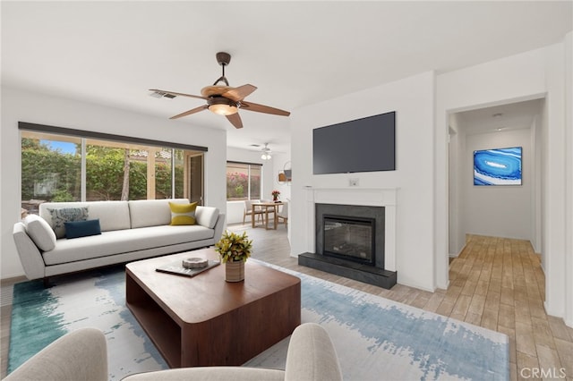 37388 Medjool, Palm Desert, CA 92211 - living area featuring ceiling fan, plenty of natural light, light wood finished floors, and a glass covered fireplace