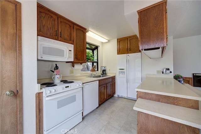 kitchen with brown cabinetry, light countertops, light tile patterned floors, a sink, and white appliances