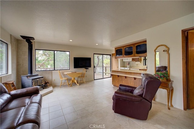living room featuring a wood stove, light tile patterned flooring, baseboards, recessed lighting, and a textured ceiling