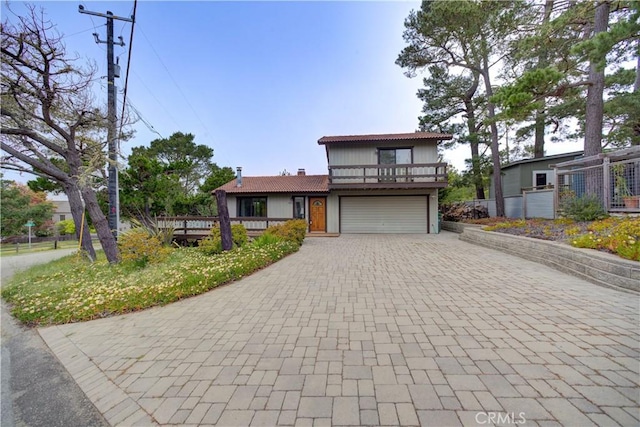 view of front of house with an attached garage, decorative driveway, and a balcony
