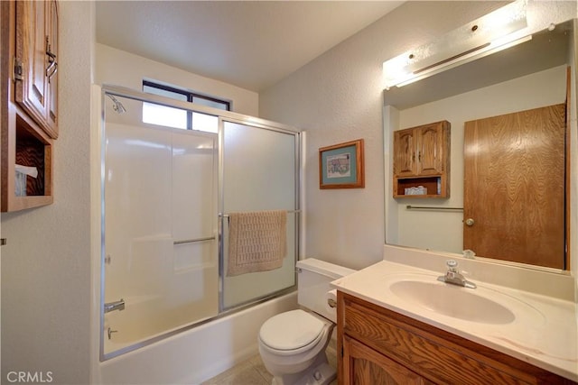 bathroom featuring vanity, shower / bath combination with glass door, a textured wall, and toilet