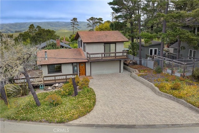 view of front facade featuring fence, decorative driveway, an attached garage, a mountain view, and a tile roof