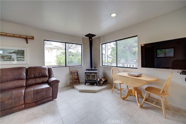 living room with a healthy amount of sunlight, baseboards, a wood stove, and a textured ceiling