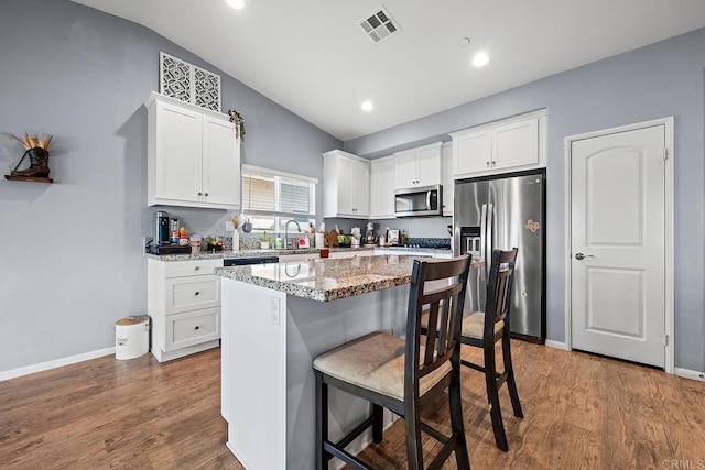 kitchen featuring white cabinets, visible vents, appliances with stainless steel finishes, and vaulted ceiling