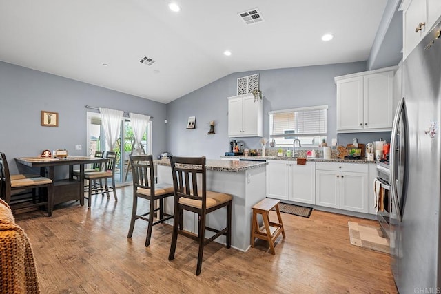 kitchen with a kitchen island, freestanding refrigerator, lofted ceiling, and visible vents