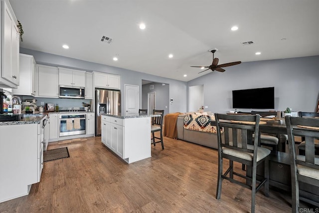 kitchen featuring ceiling fan, a kitchen bar, visible vents, appliances with stainless steel finishes, and open floor plan