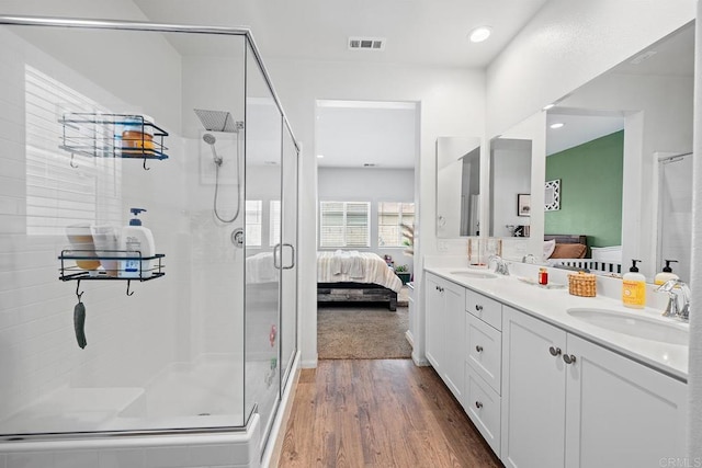 full bathroom with ensuite bathroom, a stall shower, visible vents, and wood finished floors