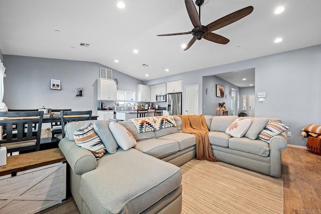 living area featuring lofted ceiling, baseboards, ceiling fan, light wood-type flooring, and recessed lighting