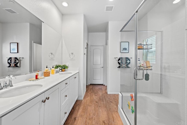 bathroom with a sink, a shower stall, wood finished floors, and visible vents
