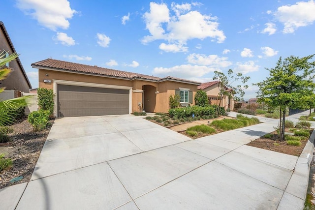 mediterranean / spanish-style home with stucco siding, an attached garage, driveway, and a tiled roof