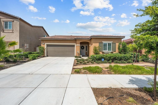 view of front of house featuring an attached garage, stucco siding, a tile roof, and concrete driveway
