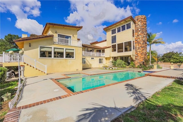 rear view of property with stairs, an in ground hot tub, an outdoor pool, and a patio