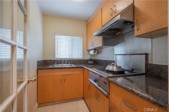 kitchen featuring a sink, light tile patterned floors, under cabinet range hood, and stovetop