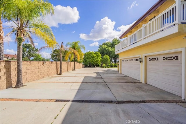 view of home's exterior with an attached garage, fence, and driveway