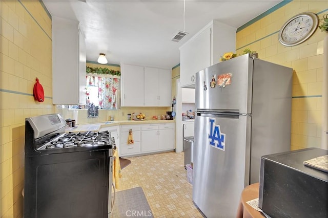 9706 Nan St, Pico Rivera, CA 90660 - kitchen featuring freestanding refrigerator, gas stove, white cabinets, tile walls, and light countertops