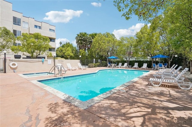 community pool with a patio and fence