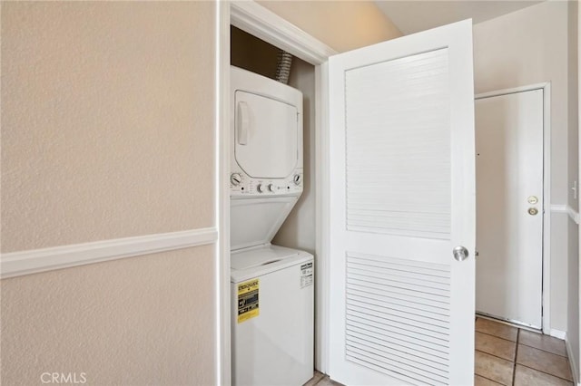 washroom featuring light tile patterned floors, stacked washer and clothes dryer, and laundry area